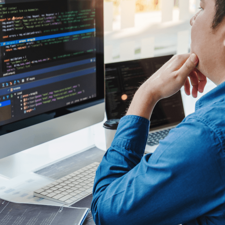 person sitting at desk looking at monitor with code on it