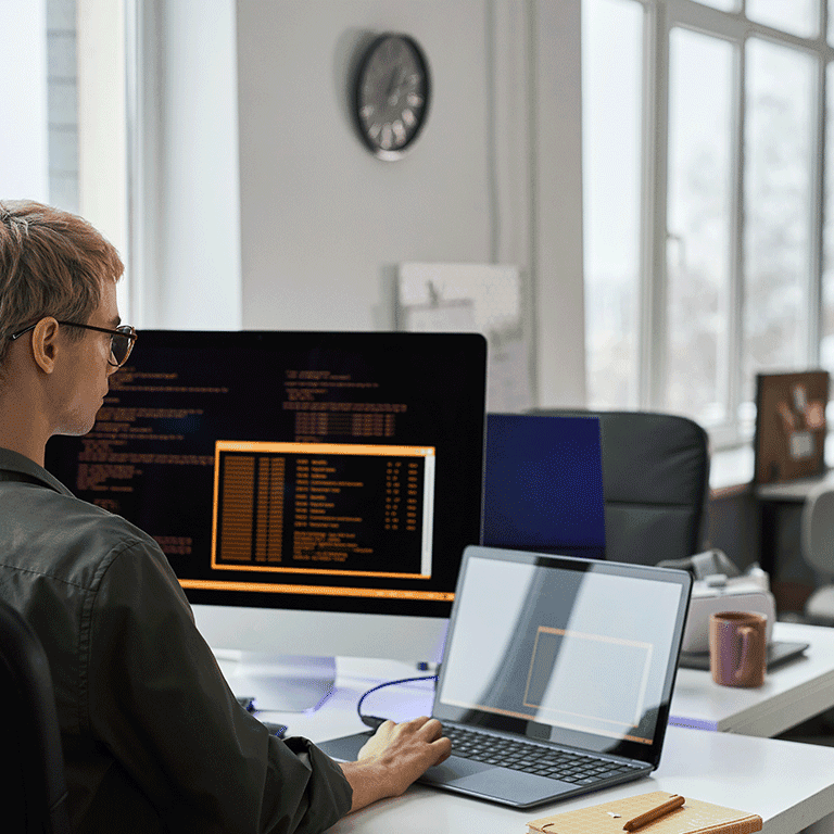 man looking at laptop and monitor