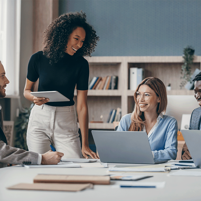 people gathered around a table with laptops and tablets