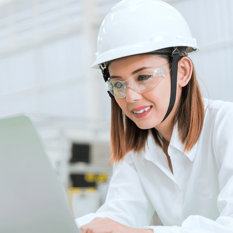 woman with hardhat and goggles looking at a laptop