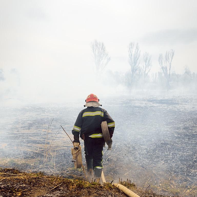 firefighter standing before smoke